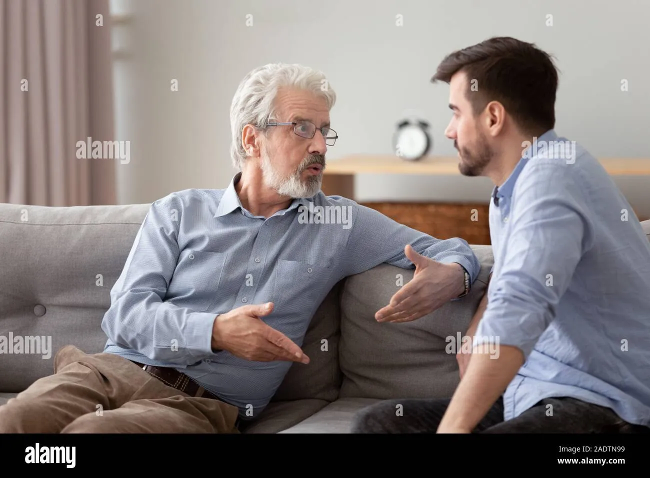serious-elderly-father-and-grownup-son-sitting-on-couch-talking-2adtn99 Rào cản thế hệ và tư tưởng cũ khiến lời xin lỗi trở nên khó khăn
